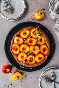 Succulent caramelised peaches on a pillowy teff millet pastry bed topped with citrus zest and pistachios; Vegan gluten-free Peach Tarte Tatin recipe. Edward Daniel ©.