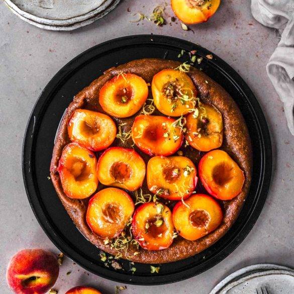 Succulent caramelised peaches on a pillowy teff millet pastry bed topped with citrus zest and pistachios; Vegan gluten-free Peach Tarte Tatin recipe. Edward Daniel ©.