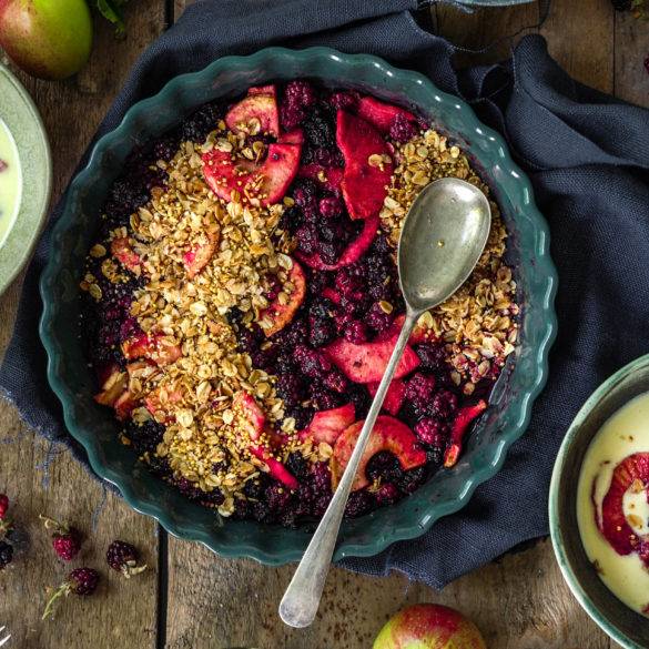 Juicy ripe burst berries covered with a layer of crunchy toasted millet and golden flaky oats; vegan gluten-free Apple and Blackberry Crumble recipe. Edward Daniel ©.