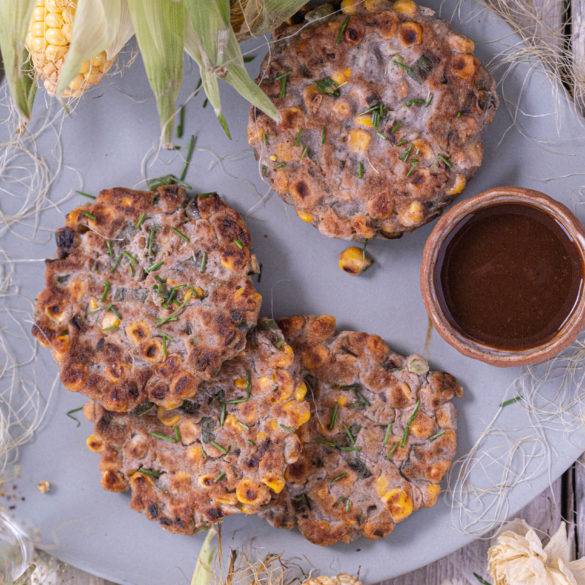 Corn Fritters Flatlay 1 Freshly picked corn on the cob battered in buckwheat, spring onion and chives with a hint of smoked paprika and liquid amino; Corn Fritters.