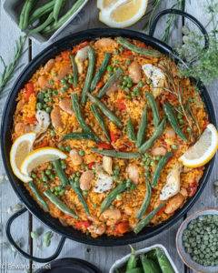Saffron sweet paprika bomba rice topped with green beans, peas, butter beans and artichokes grilled to give that burnt Vegan Paella look. 