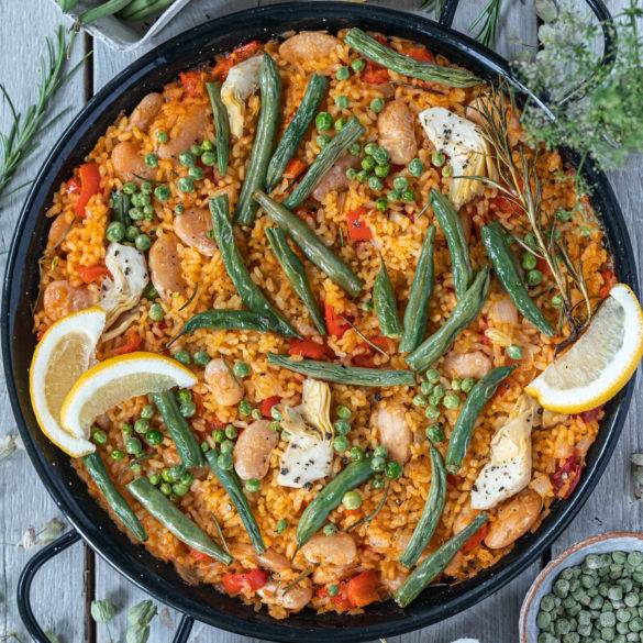 Saffron sweet paprika bomba rice topped with green beans, peas, butter beans and artichokes grilled to give that burnt Vegan Paella look. 