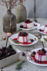 Ripe burst berry coulis on a bed of creamy coconut panna cotta with a hint of floral vanilla and minty thyme; Blackberry Panna Cotta.